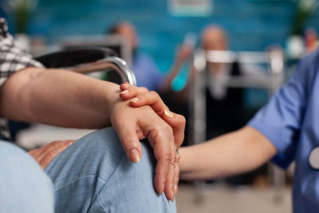 social-assistant-worker-consoling-handicapped-pensioner-patient-touching-hands