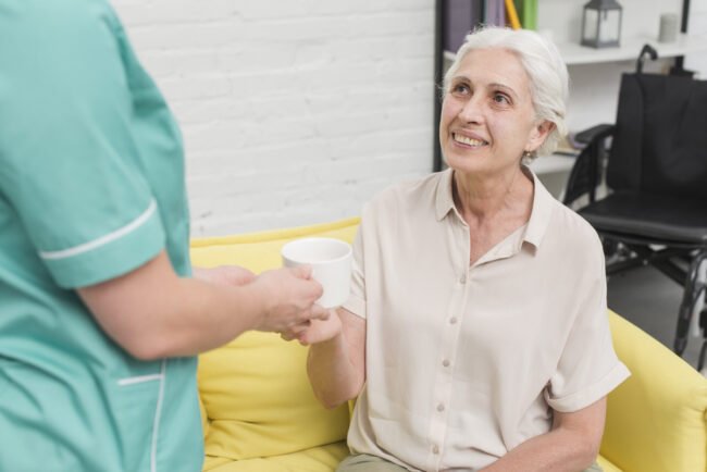 close-up-female-nurse-serving-coffee-senior-woman