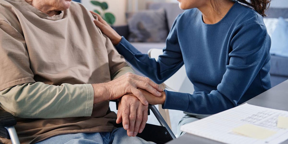 close-up-senior-man-using-wheelchair-talking-nurse-while-she-holding-his-hands-table