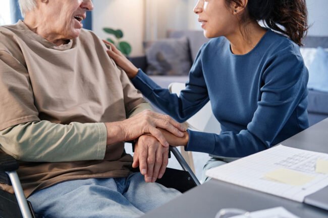 close-up-senior-man-using-wheelchair-talking-nurse-while-she-holding-his-hands-table