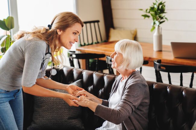 care-senior-woman-by-caretaker-home-while-sitting-couch