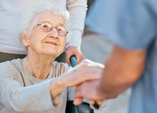 holding-hands-caregiver-and-senior-woman-in-wheel-2022-12-23-00-58-17-utc