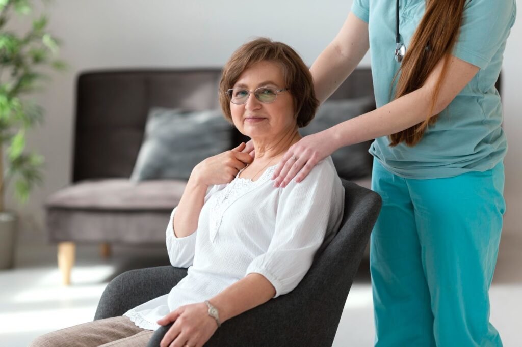 A senior woman sitting on a couch with a nurse on her side